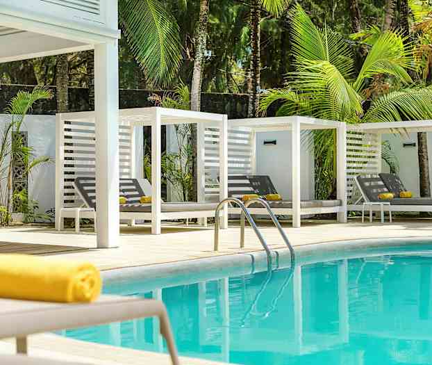 Blå swimmingpool med hvide solsenge og grønne palmer i baggrunden. (AI-genereret tekst)