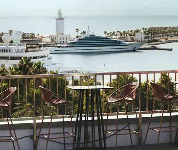 En udendørs servering med udsigt over en marina med både og et fyrtårn. (AI-genereret tekst)