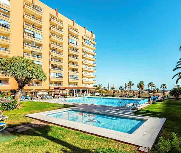 Hotelbygning med pool og have. (AI-genereret tekst)