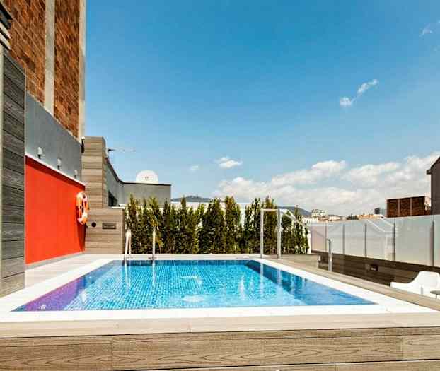 En swimmingpool på en tagterrasse med træer og bygninger i baggrunden. (AI-genereret tekst)