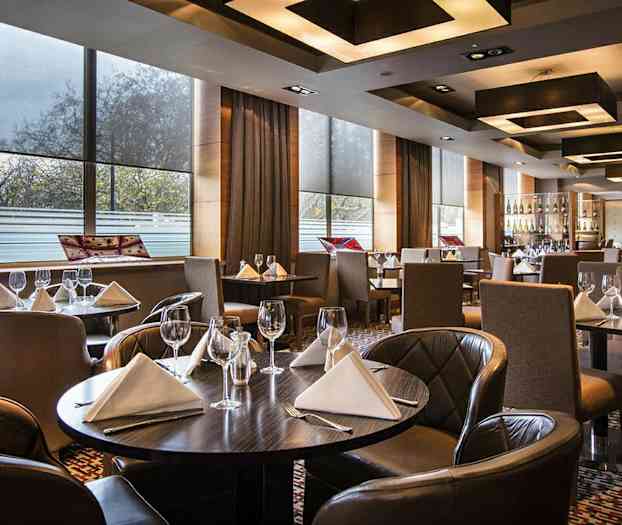 En elegant restaurant med dækkede borde med hvide servietter og vinglas. (AI-genereret tekst)