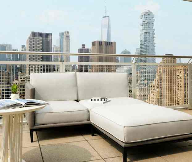 En terrasse med en lys sofa og et bord, mod baggrunden af en bysilhuet. (AI-genereret tekst)