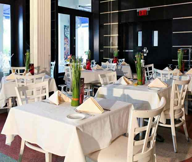 Et elegant restaurantområde med hvide borde og stole dekoreret med blomster. (AI-genereret tekst)