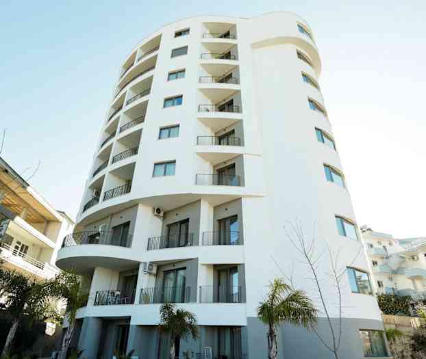 Højhus med hvid facade og altaner. (AI-genereret tekst)