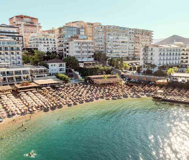 Hoteller og parasoller ved en strand med klart vand. (AI-genereret tekst)