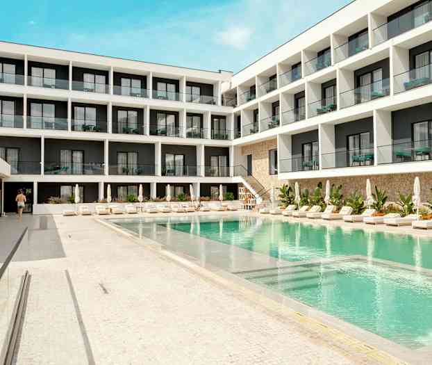 Hotelbygning med pool og liggestole i forgrunden. (AI-genereret tekst)