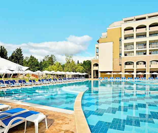 En stor pool med blåt vand omgivet af liggestole og parasoller, med et hotel i baggrunden. (AI-genereret tekst)