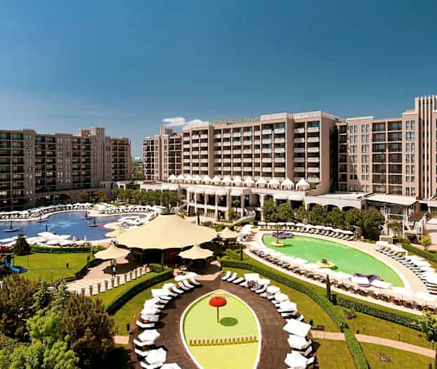 Hotelområde med store bygninger, swimmingpools og grønne områder. (AI-genereret tekst)