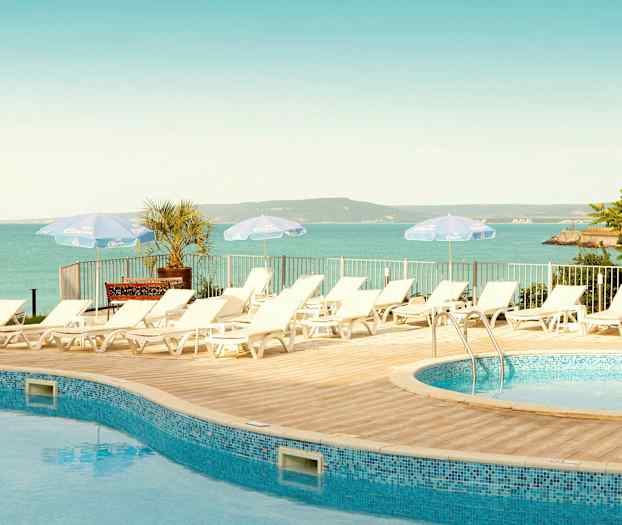 Liggestole ved en pool med udsigt over havet og landskabet. (AI-genereret tekst)