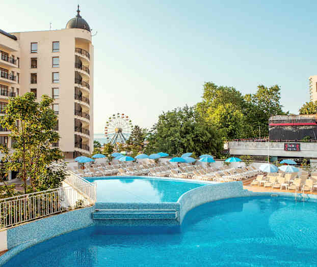 Hotelbygning med altaner, en udendørs pool og liggestole med parasoller. Baggrunden viser grønne træer og et pariserhjul. (AI-genereret tekst)