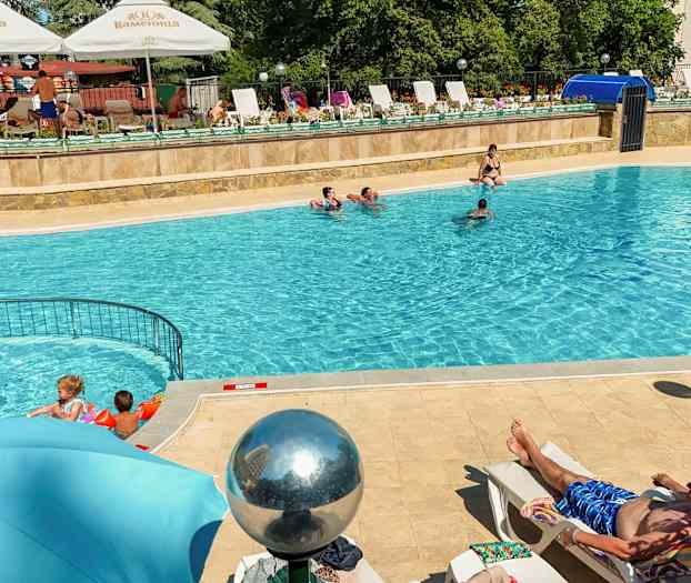 Udendørs pool med mennesker, der svømmer og solbader. (AI-genereret tekst)