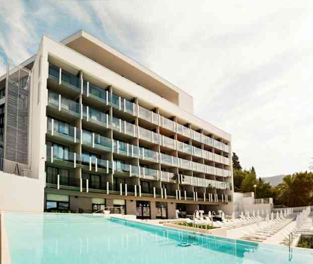 Et moderne hotel med flere altaner foran en pool. (AI-genereret tekst)