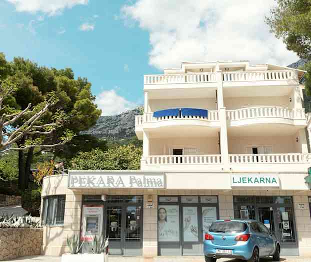 Bygning med altaner og butikker i stueetagen. (AI-genereret tekst)