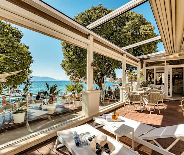 En terrasse med siddepladser, liggestole og udsigt over havet. (AI-genereret tekst)