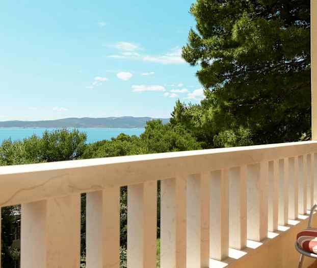 En balkon med udsigt over havet og træer. (AI-genereret tekst)