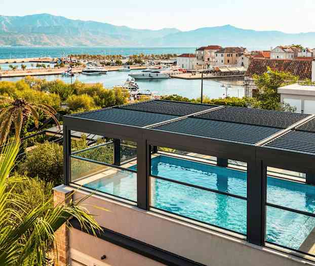 Tagterrassepool med udsigt over havn og bjerge. (AI-genereret tekst)