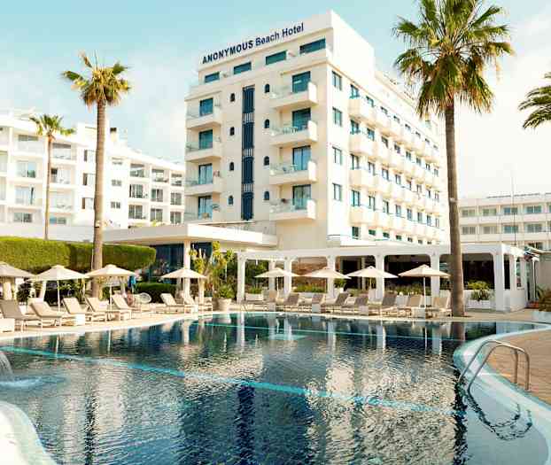 Hotel med pool, liggestole og parasoller i forgrunden. (AI-genereret tekst)