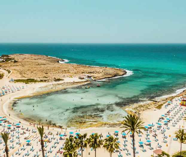 Sandstrand med parasoller og svømmende mennesker ved havet. (AI-genereret tekst)