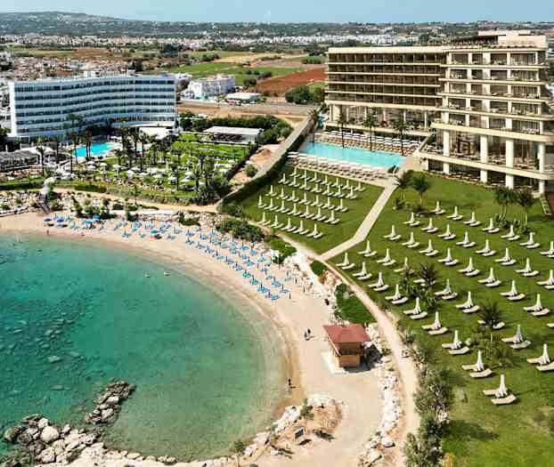 Udsigt over et hotel med poolområde nær en sandstrand og turkis vand. (AI-genereret tekst)