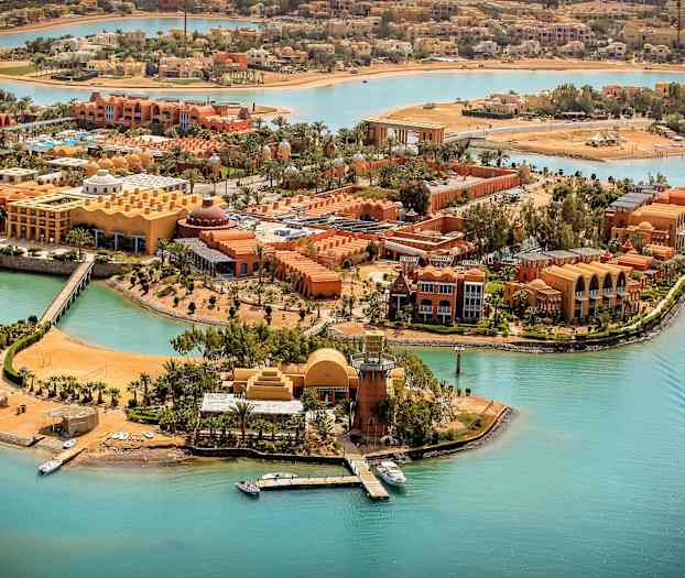 Luftfoto af et resort ved turkise kanaler med både og palmer. (AI-genereret tekst)