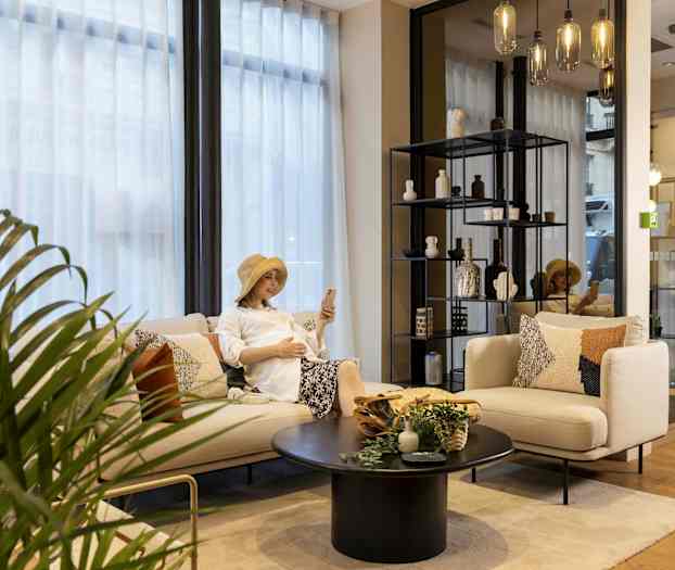 Opholdsstue med sofa, bord og hylde med dekorationer samt plante og glaslamper. (AI-genereret tekst)