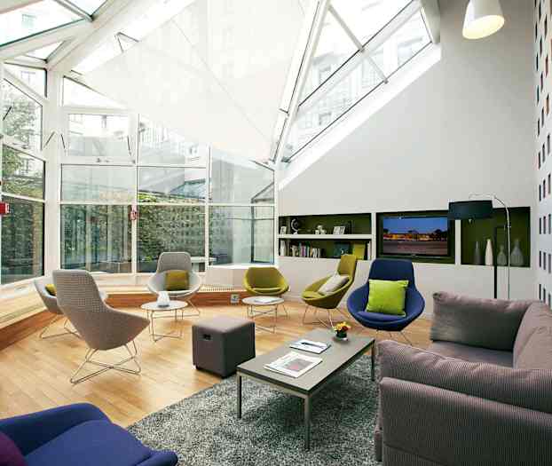 Moderne møbleret loungrum med store vinduer og komfortable siddepladser. (AI-genereret tekst)