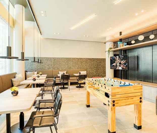 Et moderne rum med borde, stole og et bordfodboldspil. (AI-genereret tekst)