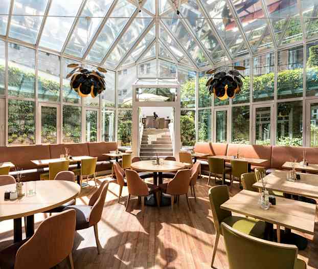 Lukket restaurant med glasvægge, siddepladser og belysning. (AI-genereret tekst)