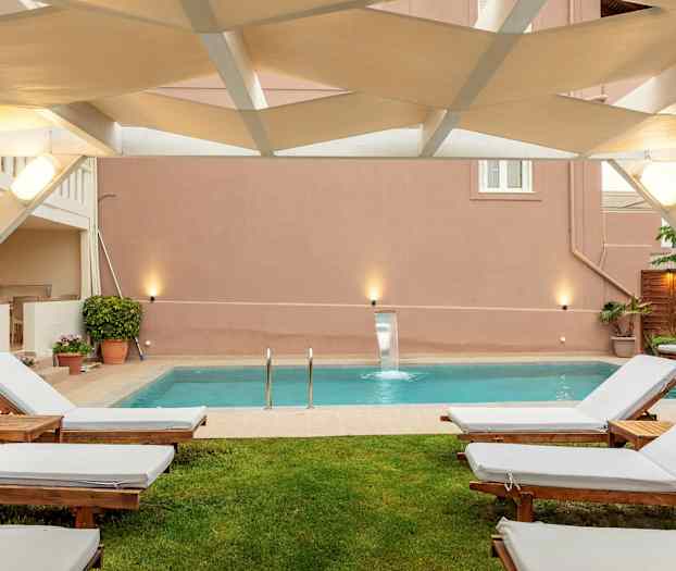 Udendørs siddeområde med liggestole og en pool. (AI-genereret tekst)