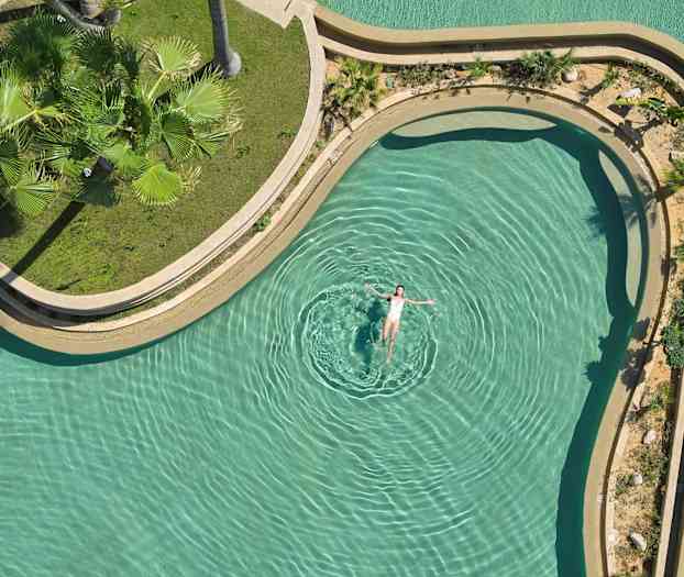 En person flyder i en pool med grønne omgivelser. (AI-genereret tekst)