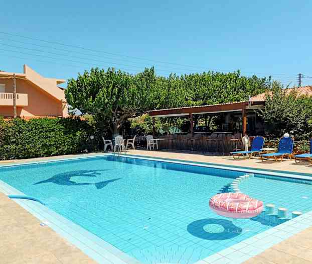 En udendørs swimmingpool omgivet af liggestole og en frodig have. (AI-genereret tekst)