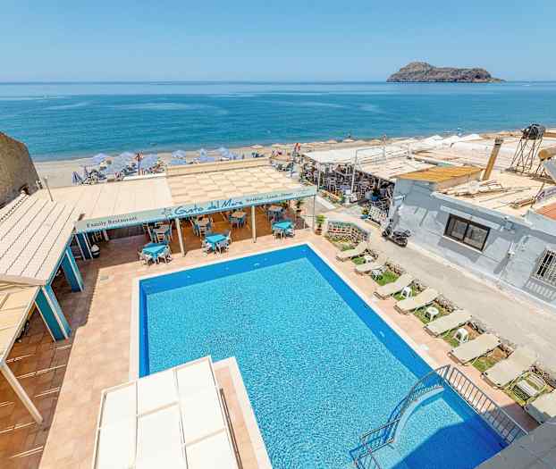 Billede af en udendørs pool med liggestole, restaurantområde og havudsigt i baggrunden. (AI-genereret tekst)