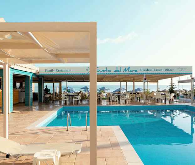 Billede af en pool ved en terrasse med restauranter ved havet. (AI-genereret tekst)