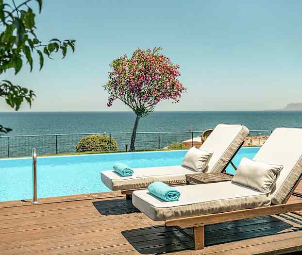 To liggestole ved en pool med udsigt over havet. (AI-genereret tekst)