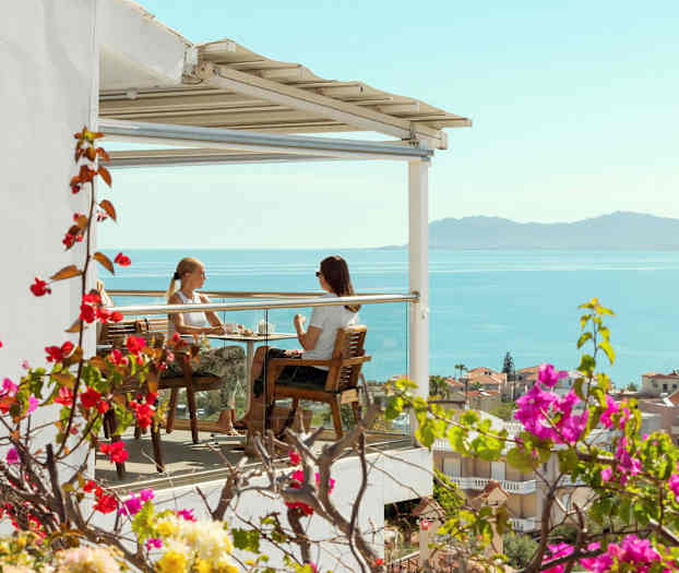 To personer sidder på en terrasse med udsigt over havet. (AI-genereret tekst)