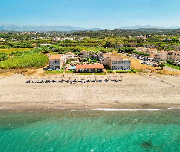 Luftfoto af strand med parasoller og ferieanlæg. (AI-genereret tekst)