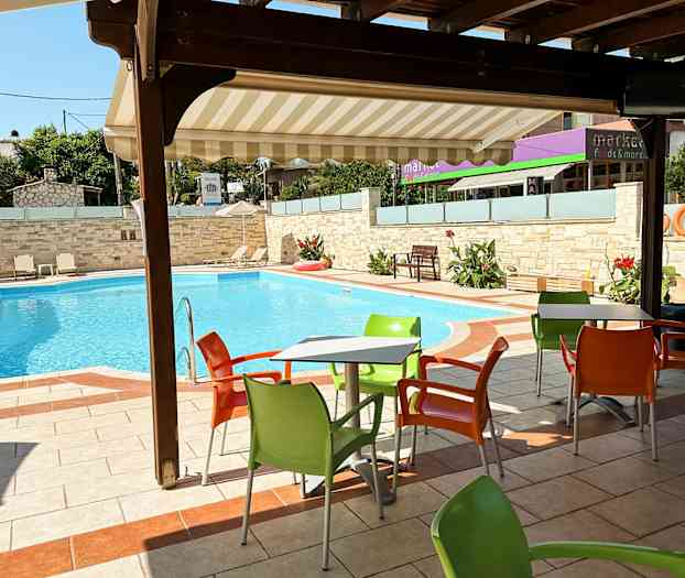 Udendørs bord med farverige stole ved en swimmingpool. (AI-genereret tekst)