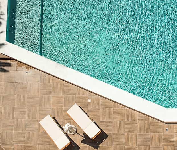 To solsenge på et trægulv ved siden af en swimmingpool. (AI-genereret tekst)