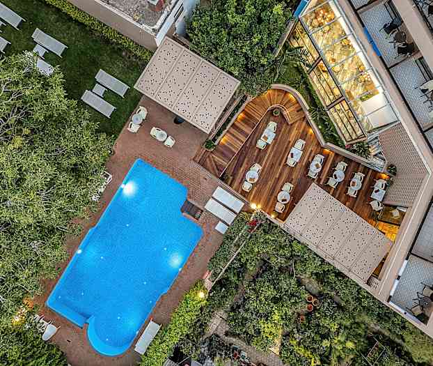 Billede af en udendørs pool, liggestole og en træterrasse med siddepladser. (AI-genereret tekst)