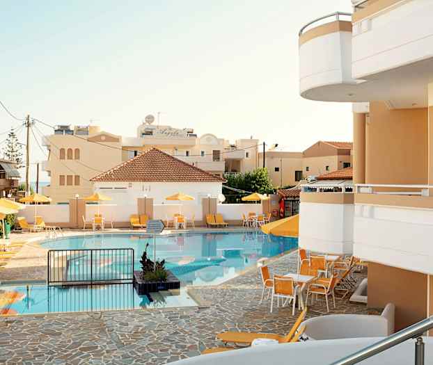 En pool med liggestole og parasoller ved et hotel. (AI-genereret tekst)