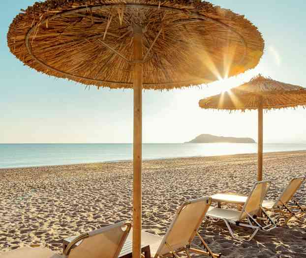 Liggestole på en sandstrand under parasoller. (AI-genereret tekst)