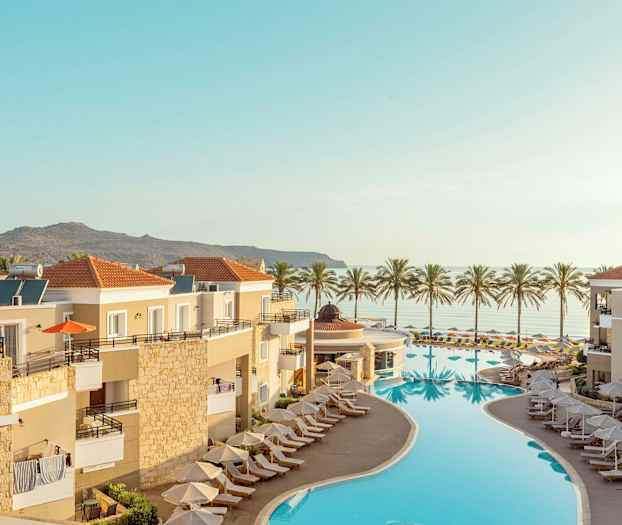 Oversigt over et resort med pool og liggestole, med havudsigt og palmer i baggrunden. (AI-genereret tekst)