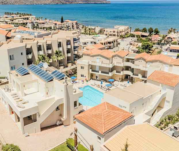 Hotelbygninger med pool og hav i baggrunden. (AI-genereret tekst)