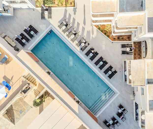 Luftfoto af en udendørs pool omgivet af liggestole og borde. (AI-genereret tekst)