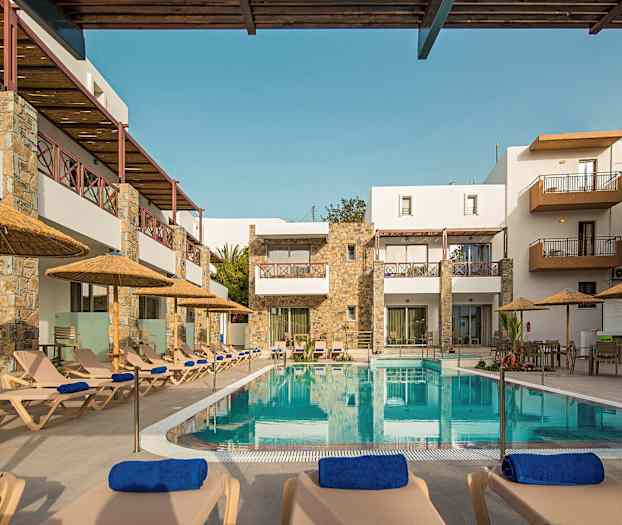 Hotellets poolområde med liggestole og parasoller foran bygningen. (AI-genereret tekst)