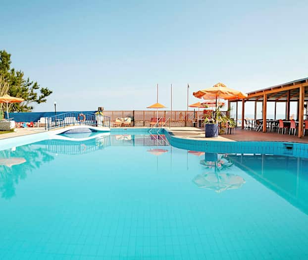 En udendørs pool med parasoller og borde ved siden af. (AI-genereret tekst)