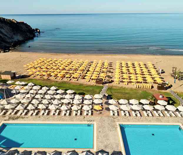 Udsigt over et poolområde med liggestole og parasoller ved stranden. (AI-genereret tekst)