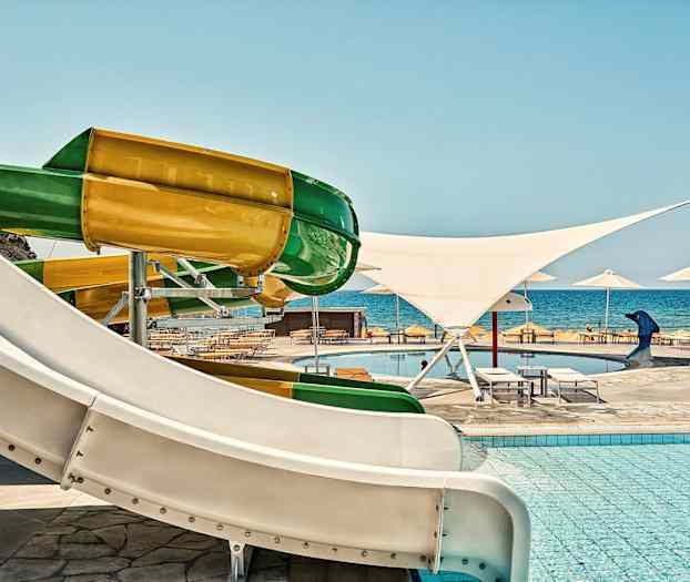 Farverige vandrutsjebaner ved en pool tæt på havet. (AI-genereret tekst)