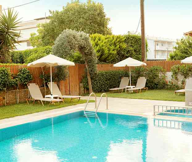 Udendørs pool med liggestole og parasoller samt frodige omgivelser. (AI-genereret tekst)