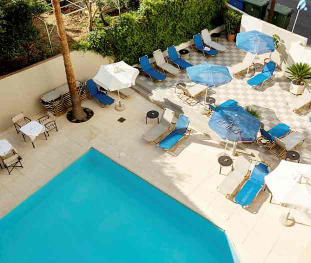 Liggestole og parasoller på en terrasse ved en pool. (AI-genereret tekst)